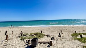 A beach with a wooden fence, a metal grill, and a clear blue sky. - Beach Front Home in beautiful Playa Encanto gated community 3bed/3bath (Playa Encanto)