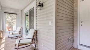 A covered porch with two rocking chairs and a door.