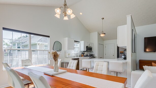 A modern kitchen with white cabinets, a microwave, and a stove.