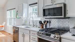 A modern kitchen with white cabinets, a stainless steel stove, and a microwave.