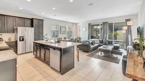 A modern kitchen with stainless steel appliances, a central island, and a dining area with a sofa and coffee table.