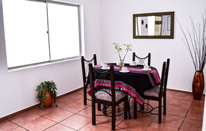 Enjoy meals in this dining area with a round table for four, a vase with a branch, and a potted plant.