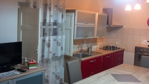 A compact kitchen with a dining area, featuring a TV, a refrigerator, a sink, and a stove. - Beautiful villa located in a residence a stone's throw from the sea in an oasis of relaxation (Sicilia)