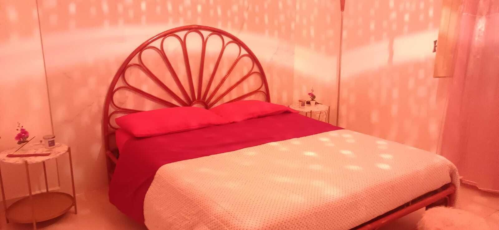 A bedroom with a bed, a nightstand, and a wall-mounted shelf.