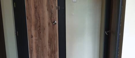 A room with a wooden door, a light switch, and a dark floor.