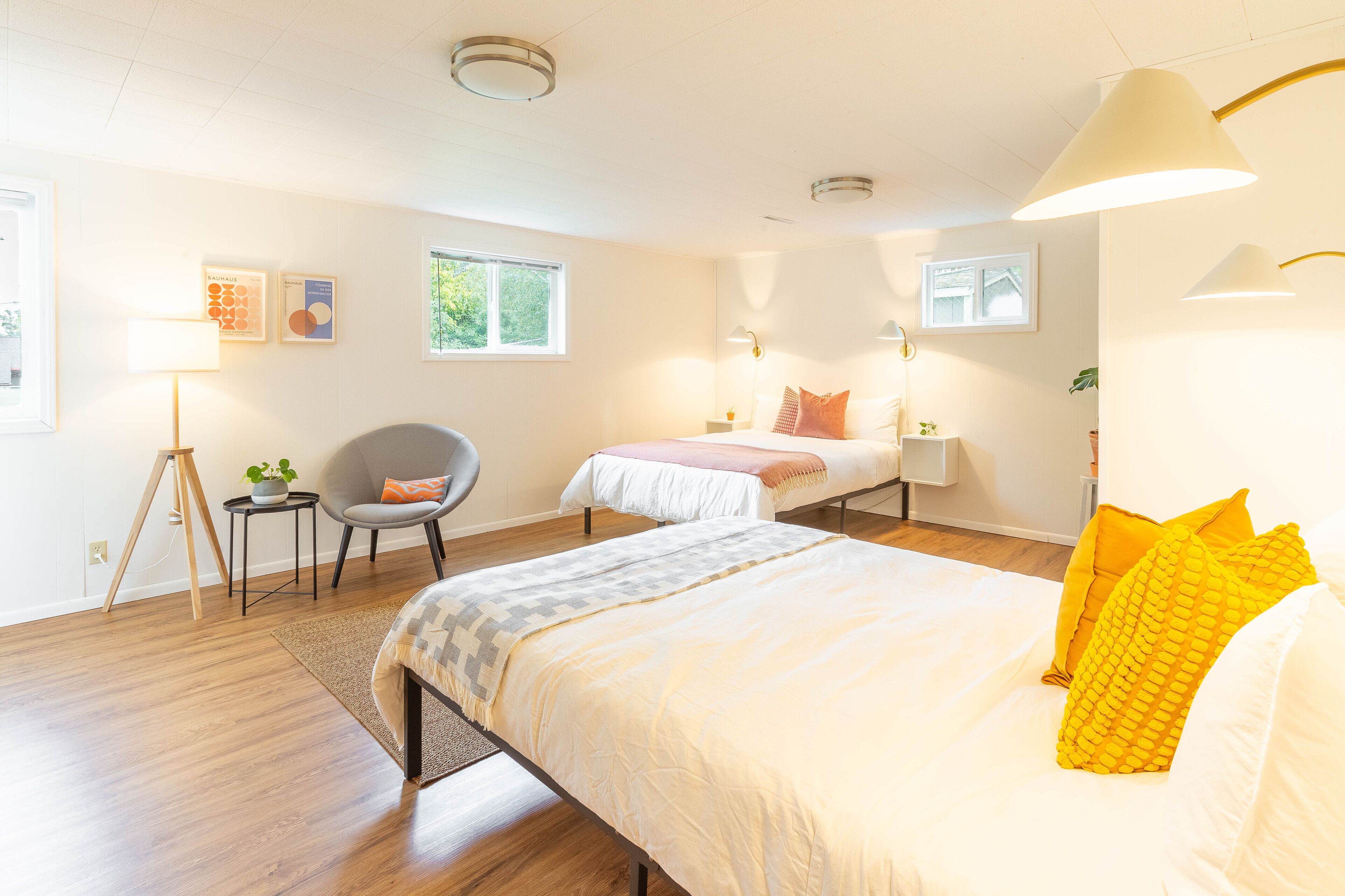 Et moderne soveværelse med en stor seng, en mindre seng, en stol og et skrivebord med lampe.