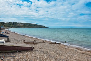 Une plage de galets avec des bateaux et une structure en bois.