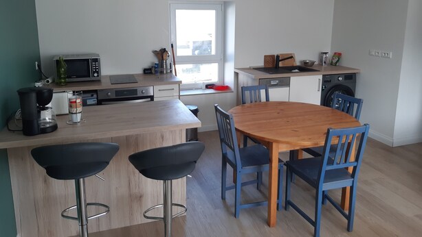 Ett modernt kök med en köksö i trä, barstolar, en mikrovågsugn och en kaffemaskin.