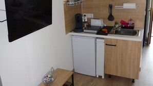 Una cocina compacta con microondas, tostadora y refrigerador pequeño.