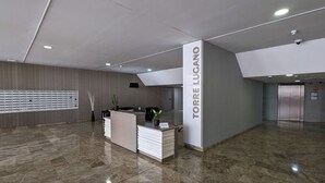 A modern reception area with a marble floor, a reception desk, and a wall-mounted display. - TORRE LUGANO sea view apartment (Benidorm)