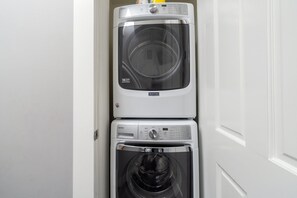 A stacked washer and dryer unit in a hallway.