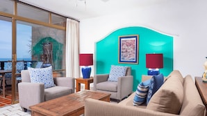 A modern living room with a teal accent wall, two armchairs, a sofa, a wooden coffee table, and a large vase. - Condominium Playa Bonita (Puerto Vallarta)