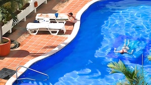 A swimming pool with a tiled deck, lounge chairs, and a palm tree. - Condominium Playa Bonita (Puerto Vallarta)