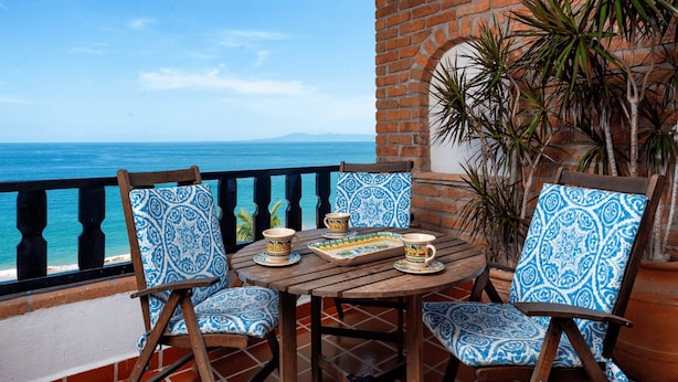 A terrace with a view of the sea, featuring a wooden table with chairs and a tiled wall. - Condominium Playa Bonita (Puerto Vallarta)