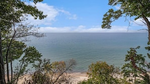 Ein Strand mit klarem Wasser, umgeben von Bäumen und blauem Himmel.