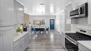 A modern kitchen with white cabinetry, a dining area with a blue door, and a large stove. - Stylist Home In Convenient  Location New Listing Special Book Now! (Temple City)