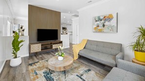 A modern living room with a flat-screen TV, grey sofa, wooden accents, and a patterned rug. - Stylist Home In Convenient  Location New Listing Special Book Now! (Temple City)