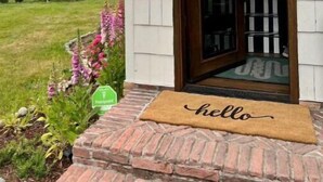 A house with a white exterior, a wooden door, and a brick entrance. - Hood Canal Beach Retreat (Belfair)