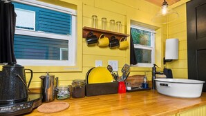 A kitchen with a wooden countertop, a coffee maker, a sink, and various utensils. - The Arthur - Custom Tiny Home w/ Train Vibe (Portland)