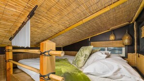 A dorm-style room with a bamboo ceiling, bunk beds, and a window with a view. - The Bamboo - Custom Tiny Home w/ Bamboo Vibe (Portland)