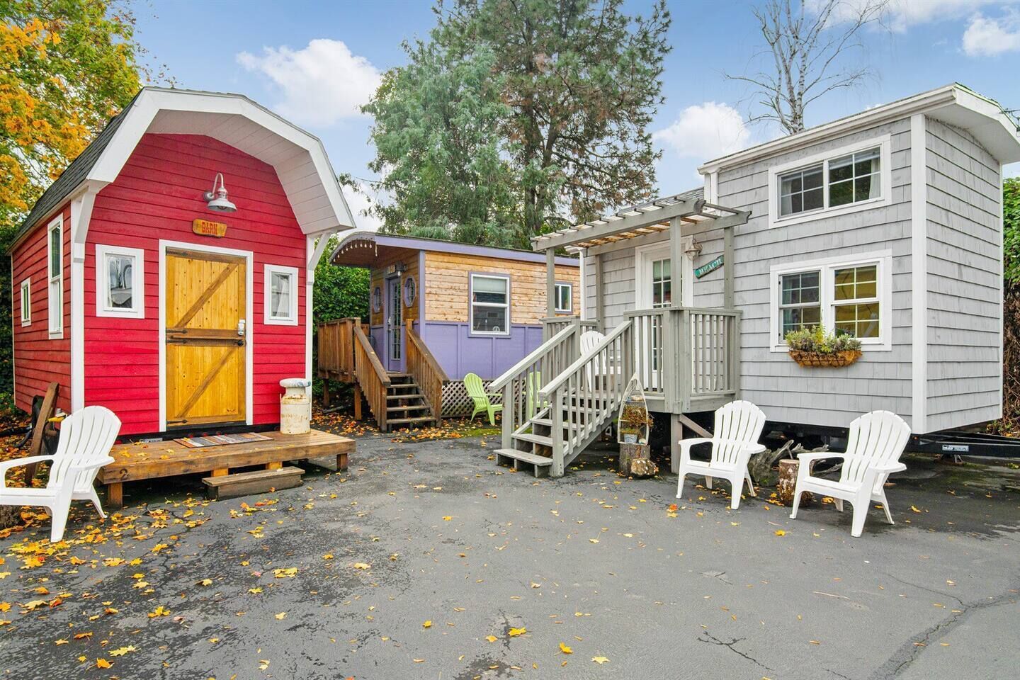 A red and gray cabin with a porch, a staircase, and a small deck with white chairs.