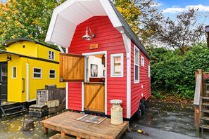 A red mobile home with a white roof, a wooden door, and a small porch area. - The Barn - Custom Tiny Home w/ Barn Vibe (Portland)