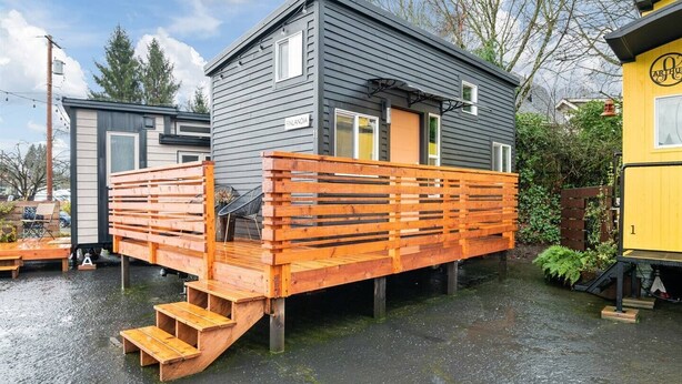 A two-story house with a wooden deck and a small staircase leading to the entrance. - The Finlandia - Custom Tiny Home w/ Finnish Vibe (Portland)