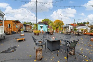 An outdoor patio with seating, a fire pit, and string lights.