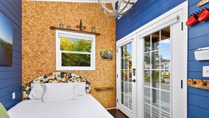 Un dormitorio con una cama, una ventana, una puerta y una pared con un tablón de corcho.