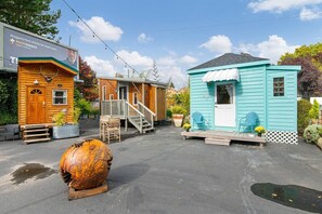 A small wooden cabin with a porch and a blue house with a white door.