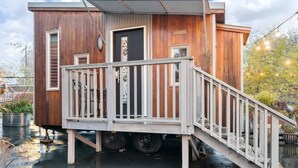 A modern wooden cabin with a deck and a ramp leading to the entrance. - The Modern - Custom Tiny Home w/ Modern Vibe (Portland)