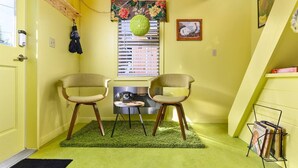 Une petite pièce accueillante, avec deux fauteuils, une table, un téléphone ancien et une boule décorative suspendue.