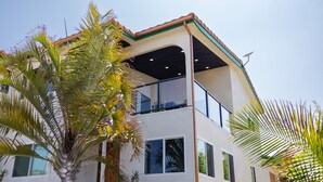 Un edificio de dos pisos con un balcón en el nivel superior, rodeado de palmeras.