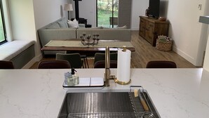 Eine moderne Küche mit Spüle, ein Essbereich mit Tisch und Stühlen, eine Couch und ein Fernseher.
