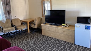 A hotel room with a TV, microwave, and two chairs. - Budget Inn Motel (Woodburn)