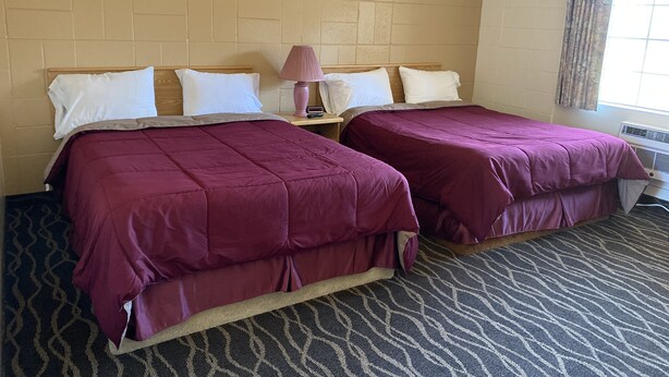 A hotel room with two beds, a nightstand, a lamp, and a framed picture on the wall. - Budget Inn Motel (Woodburn)