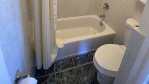 A bathroom with a bathtub, toilet, and shower curtain. - Budget Inn Motel (Woodburn)