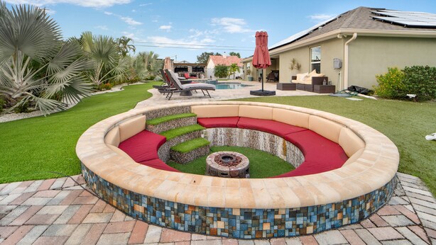 Un espacio de estar al aire libre circular con un brasero, rodeado por un borde con mosaicos.
