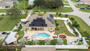 Una propiedad residencial con piscina, paneles solares y un patio cercado.