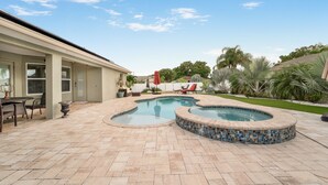 Un patio trasero con piscina, mobiliario de jardín y una zona de estar cubierta.