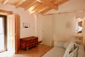Une chambre avec un plafond en bois, un placard avec une porte coulissante, un lit avec des oreillers et une petite commode en bois.