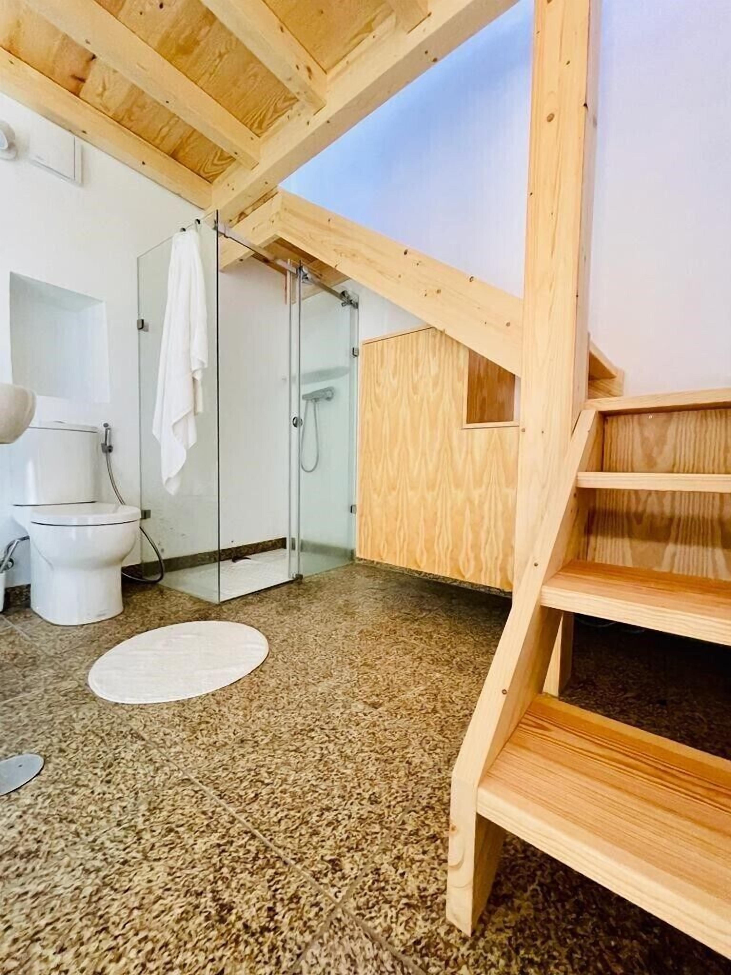 Ein Badezimmer mit Holzboden, einer Dusche, einer Toilette und einem Waschbecken.