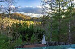 A forested area with a wooden deck and a green roofed structure. -  Quiet hideout w/ Hot Tub & fire pit! BrysonCity! Pet Friendly! GSMR NOC  (Bryson City)