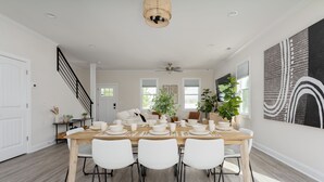 A dining area with a wooden table set for six, white chairs, and a ceiling fan. - DT Oasis ~ Great Amenities, WFH Set-up, Outdoor Dining, Tennis & Pickleball (Wilmington)