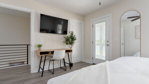 A bedroom with a bed, a desk, a chair, a TV, and a door. - DT Oasis ~ Great Amenities, WFH Set-up, Outdoor Dining, Tennis & Pickleball (Wilmington)
