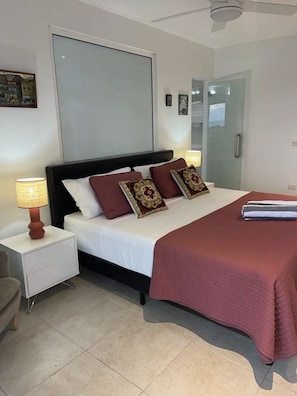 A modern bedroom with a bed, nightstands, and a glass door.