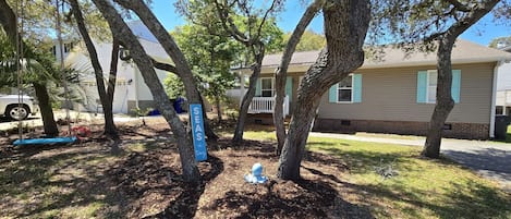A residential area with trees, a swing, and a house with a porch.