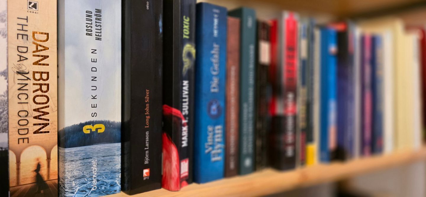 A bookshelf with books, including titles like "The Da Vinci Code" and "The Silent Patient".