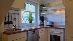 A compact kitchen with a dishwasher, oven, and a coffee maker.