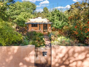 A house with a covered porch, surrounded by dense vegetation and trees. - Adorable Santa Fe 3 Bedroom Home! (Santa Fe)